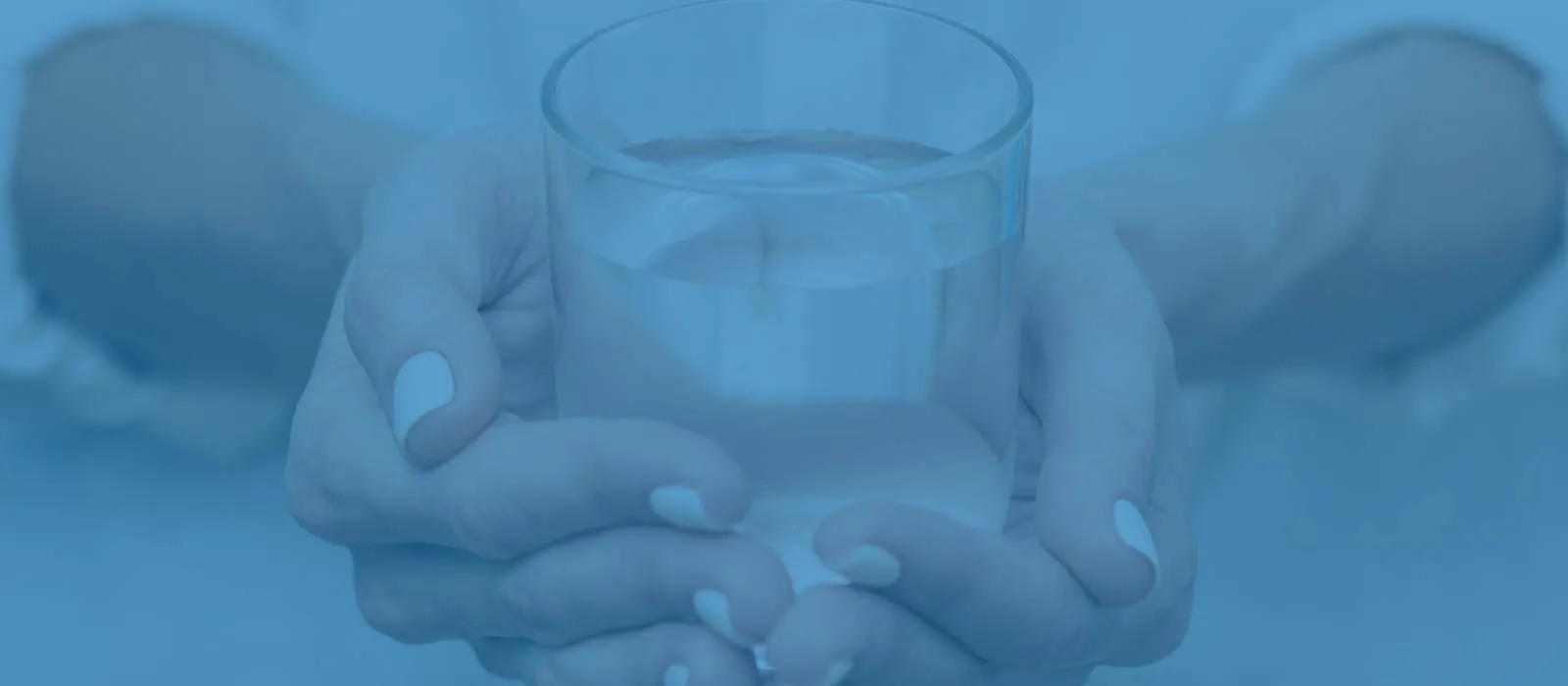Mãos segurando um copo de água purificada